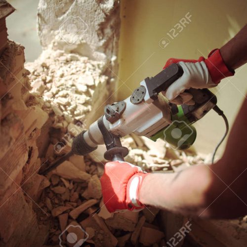 129273758-home-renovation,-builder-with-hammer-breaking-wall-indoors