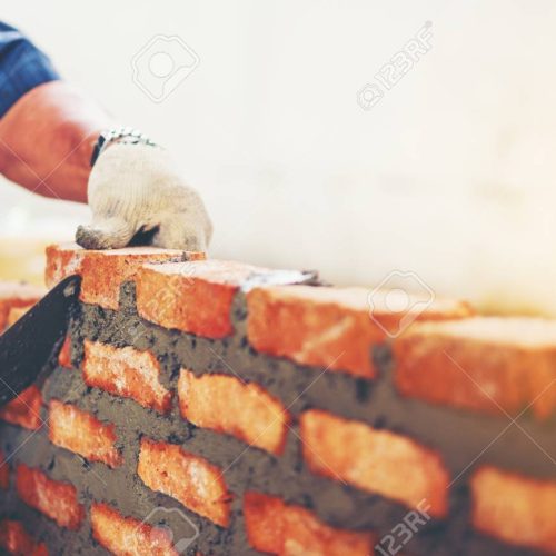 Old man Hand white-wash cement built wall brick new house, Bricklayer worker installing brick masonry on exterior wall with trowel putty knife  local county in Thailand